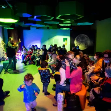 Familias con niños y niñas en sala con artista